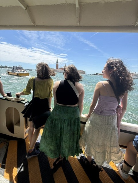 Three students look out at a body of water in Italy