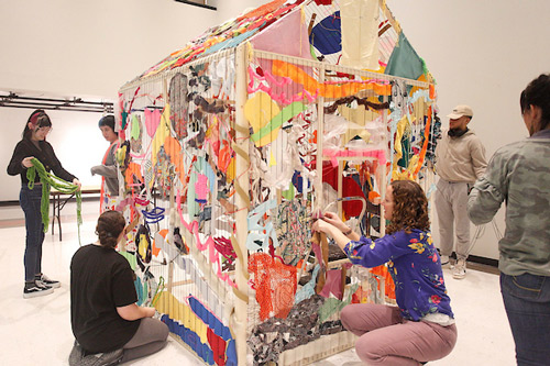 Students create a textile sculpture together using a frame of a small house