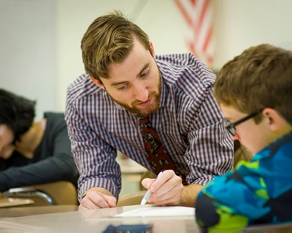 teacher helping student at their desk