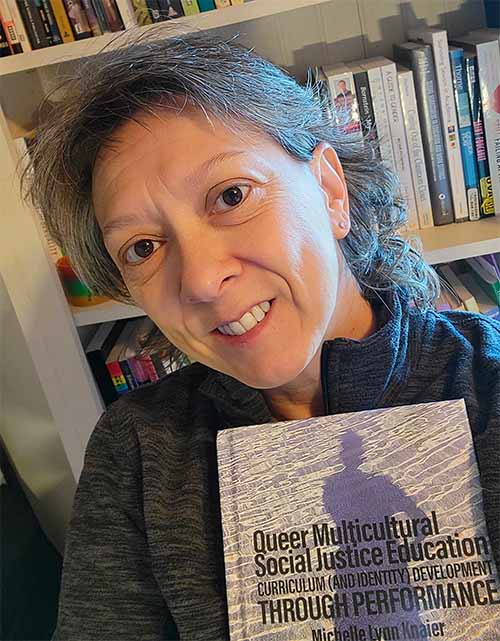 Michelle Knaier holding her publication: Queer Multicultural Social Justice Education