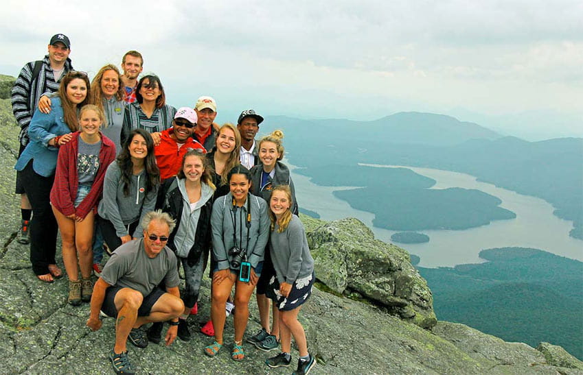 Broyles posing on a mountain top with a group of students