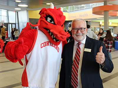 Doug Langhans gives a thumbs-up with Blaze, the red dragon mascot