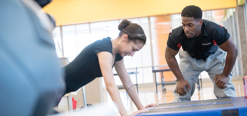 A personal trainer assisting a student with pushup form