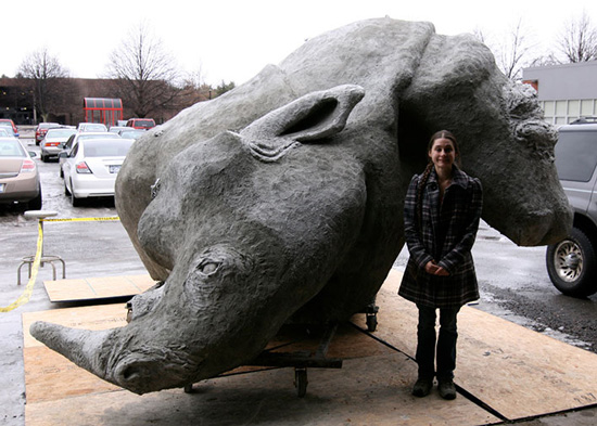 A student standing in front of a large sculpture of an abstract rhinoceros