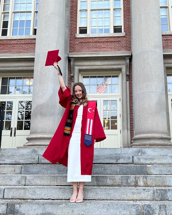 Student standing on steps of Old Main in graduation robes