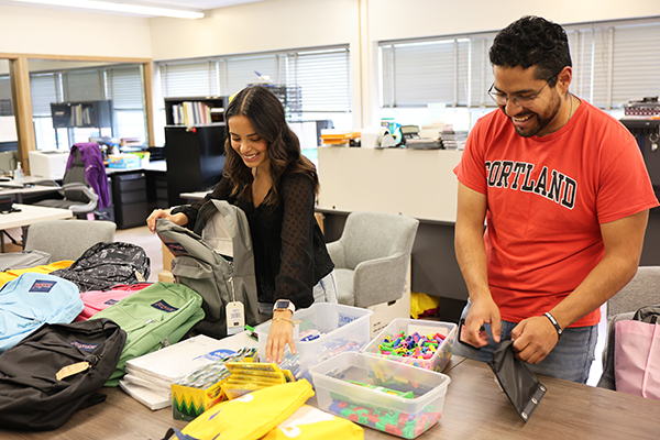 Andy Rivera and Daniel Arevalo, migrant educator for the METS Program, fill backpacks with school supplies.