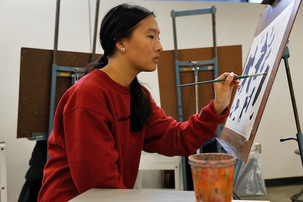 Student painting on an easel in a painting class