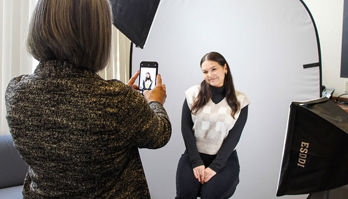 Career Services staff member taking a student photo for LinkedIn