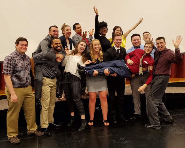 A group of students in a silly group photo at a sports management celebration