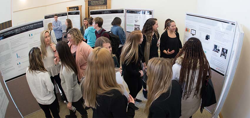 Students and faculty gathering to discuss poster presentations