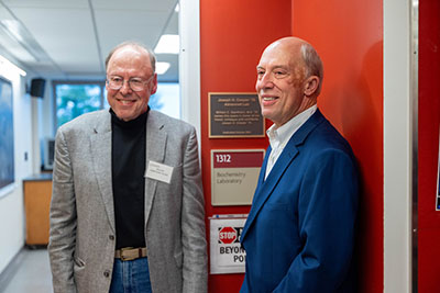 Dr. Bill Baerthlein stands next to Joe Cooper and both smile outside the doorway to the Cooper Advanced Lab