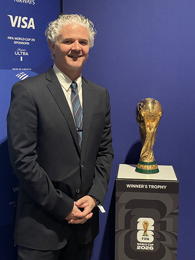 Iain Nelson stands next to the FIFA World Cup