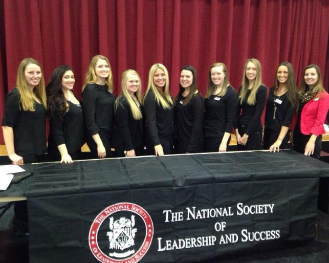 Students posing behind a banner that reads "National Society of Leadership and Success"