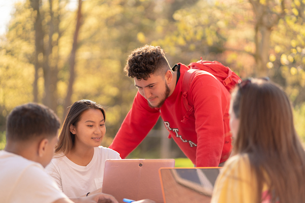 Students looking at laptops outside