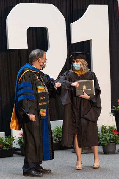 Graduate student bumping elbows with President Bitterbaum