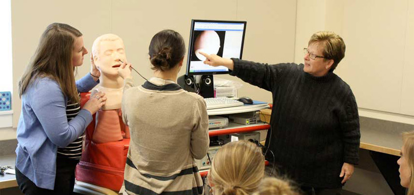 Communication Disorders and Sciences instructor showing students how to use equipment in classroom