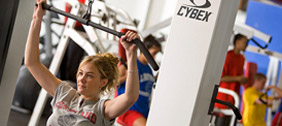 A student working out in the Student Life Center circuit / free weight area..