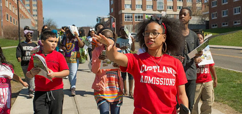 A SUNY Cortland student gives a campus tour to a diverse group of high school students.